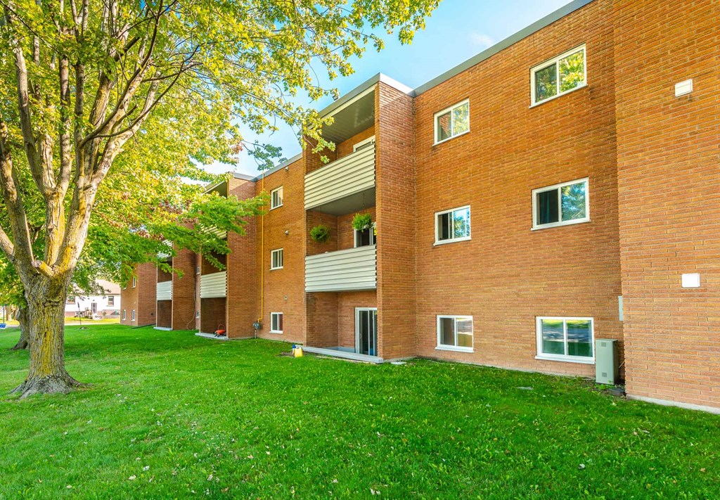 a large brick building with green grass and a tree