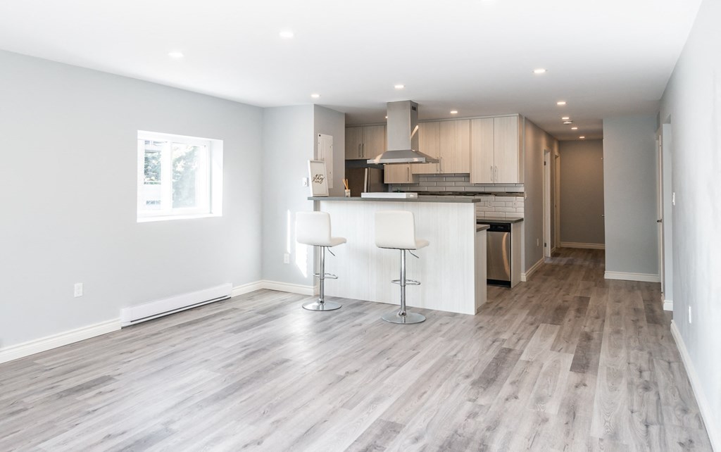 a living room with a kitchen and a wooden floor