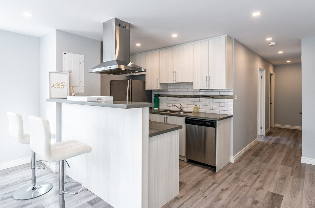 a white kitchen with a bar and a stainless steel stove