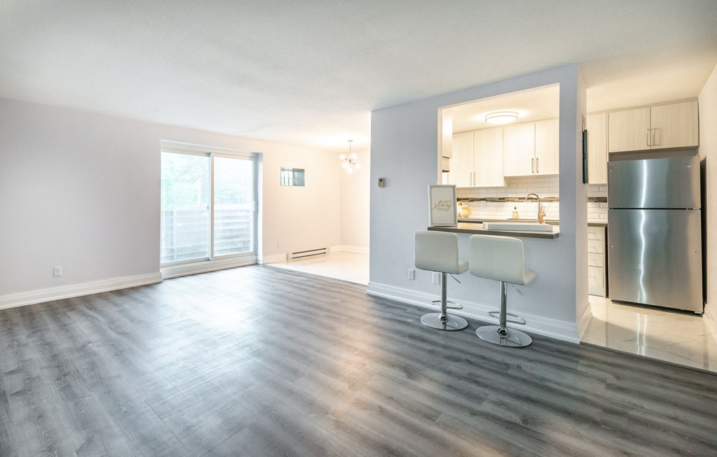 an empty living room and kitchen with a stainless steel refrigerator