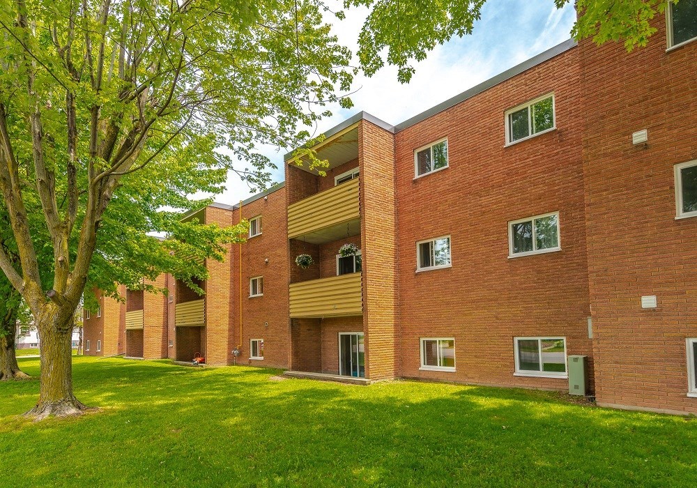a row of red brick apartment buildings on a green lawn