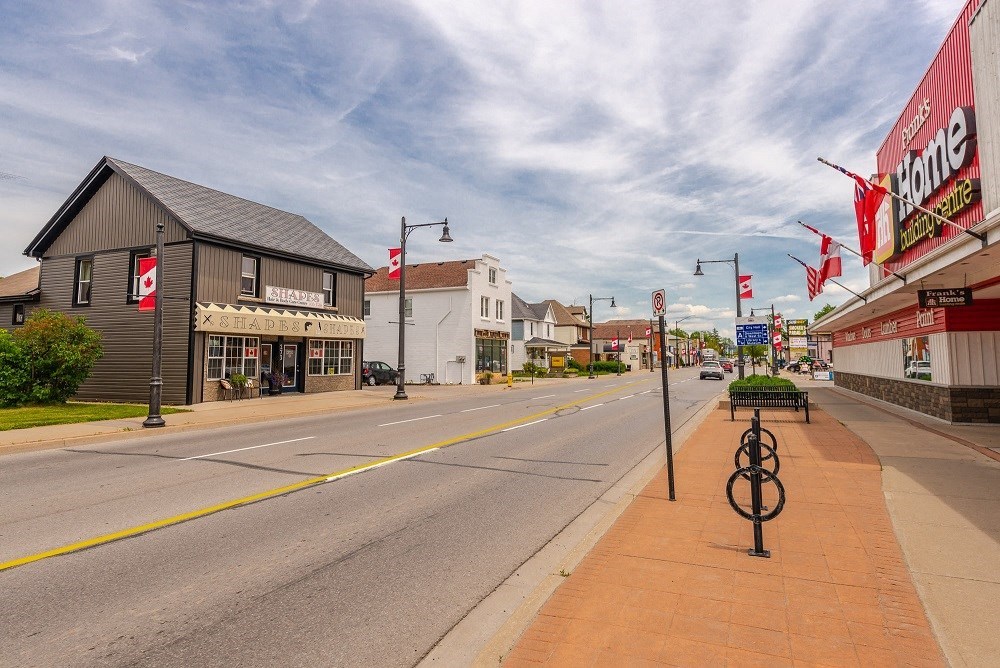 a city street with stores and a bench on the side of the road