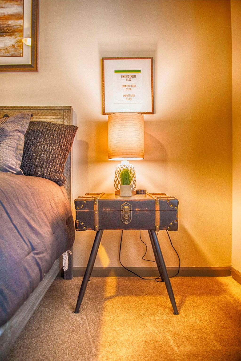 a bedroom with a suitcase table with a lamp and a bed