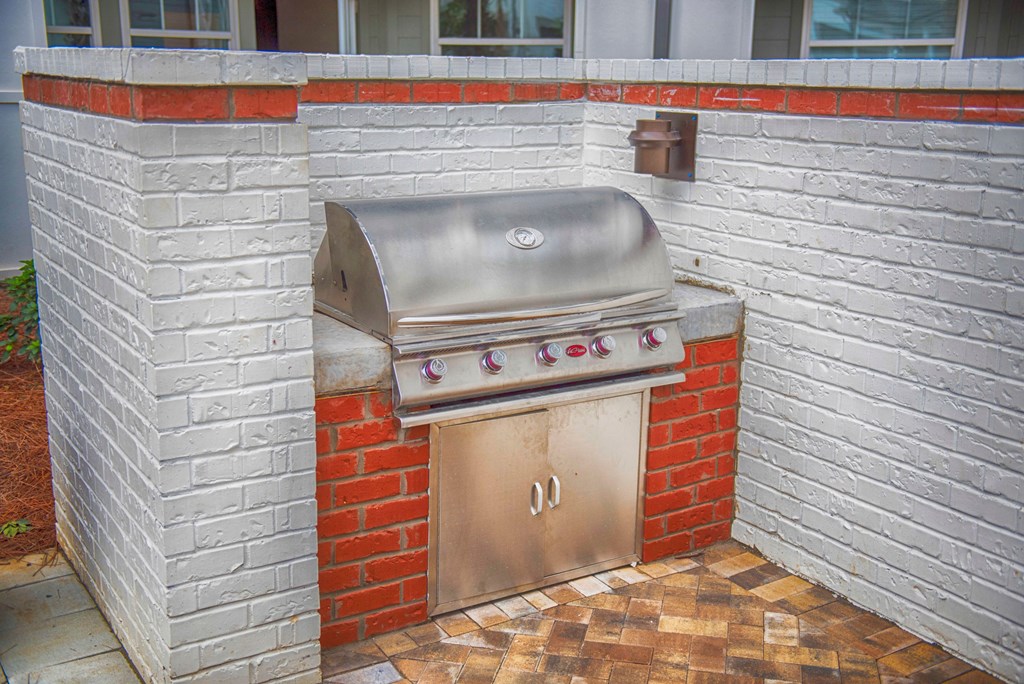 a stainless steel barbecue grill in the corner of a brick wall