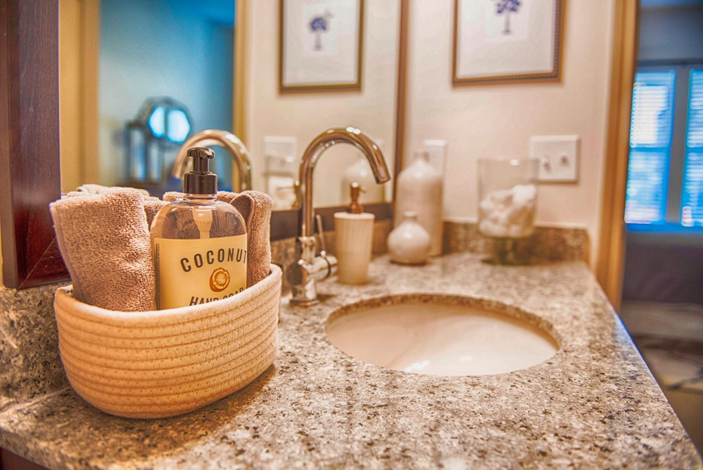 a bathroom sink with soap and a basket on it