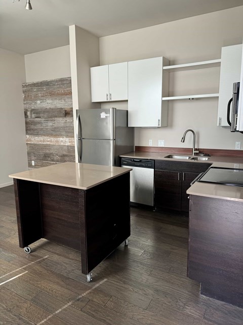 A kitchen with a refrigerator, sink, and cabinets.