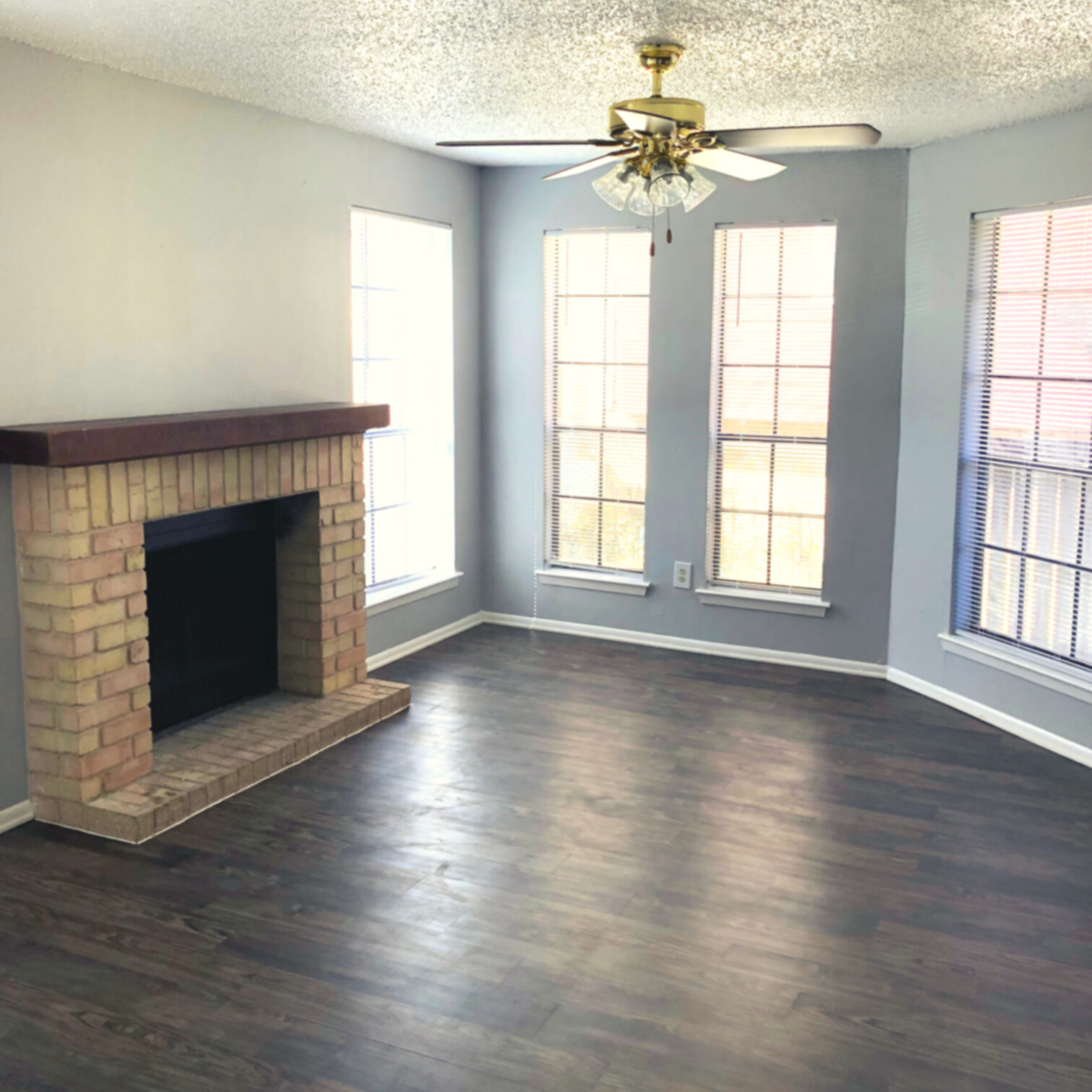 Living room with dark wood flooring and grey walls, 4 wall length windows