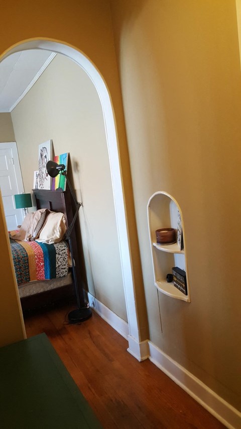 an arched door way into a room with a bed and shelves
