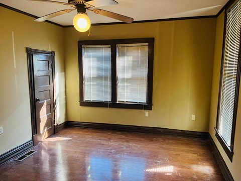 an empty living room with a ceiling fan and two windows