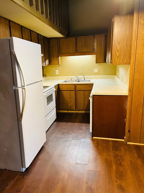 A white refrigerator stands in a kitchen with wooden cabinets.