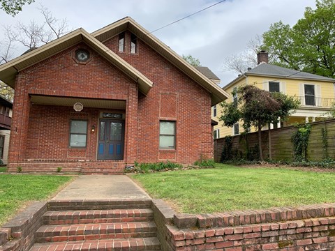 A red brick house with a blue door and a small porch.