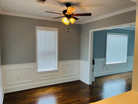 a living room with white walls and a ceiling fan