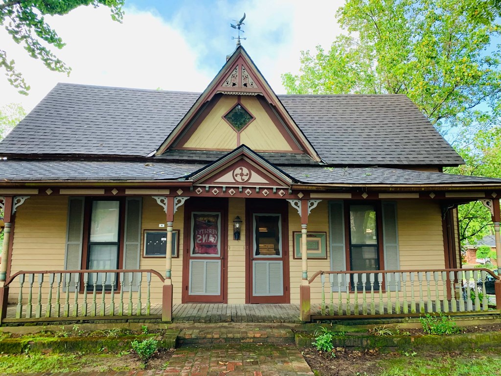 a yellow house with a steep roof and a porch