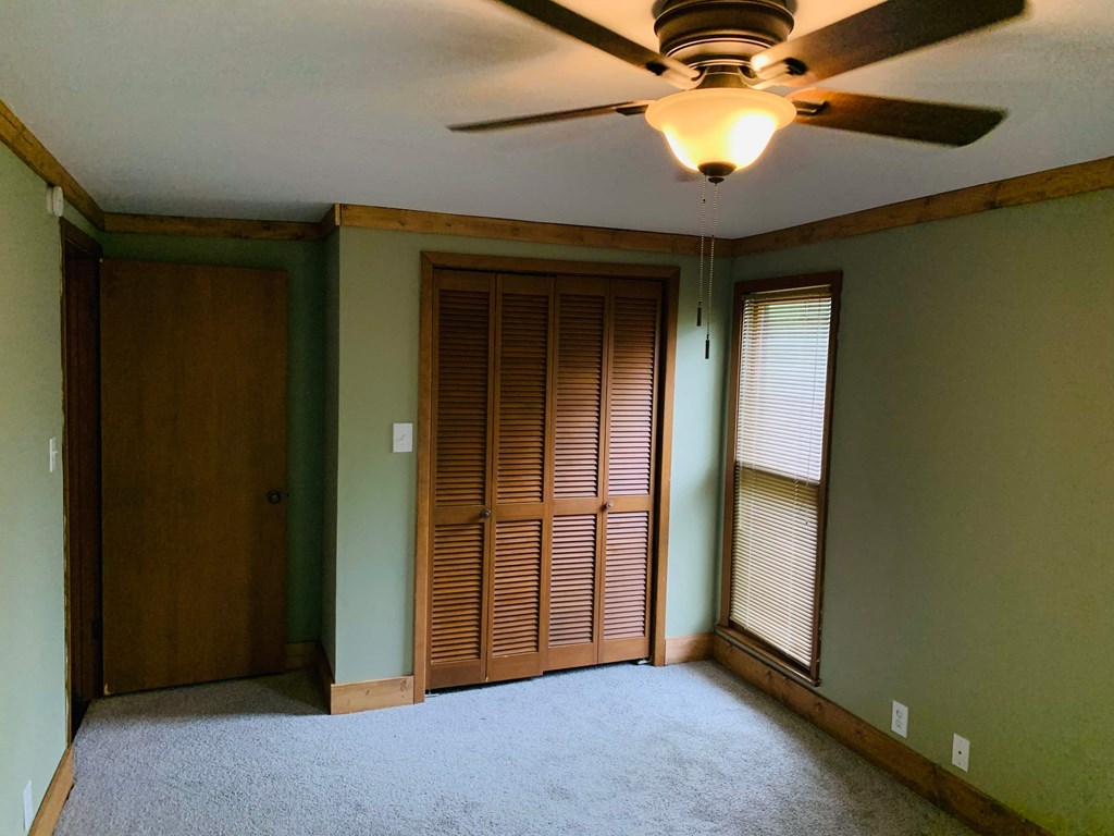 an empty living room with a ceiling fan and a closet