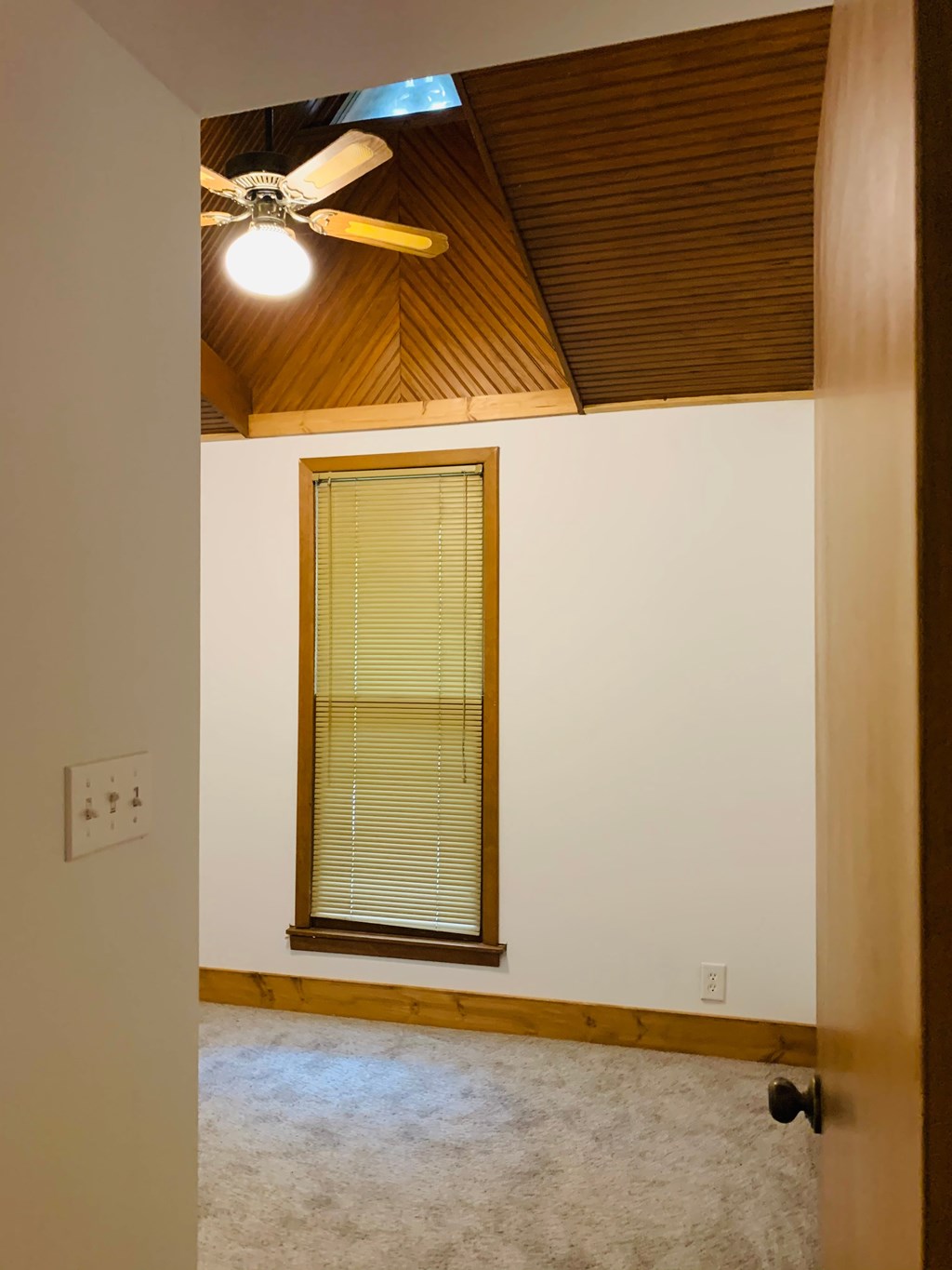 an empty room with a window and a ceiling fan