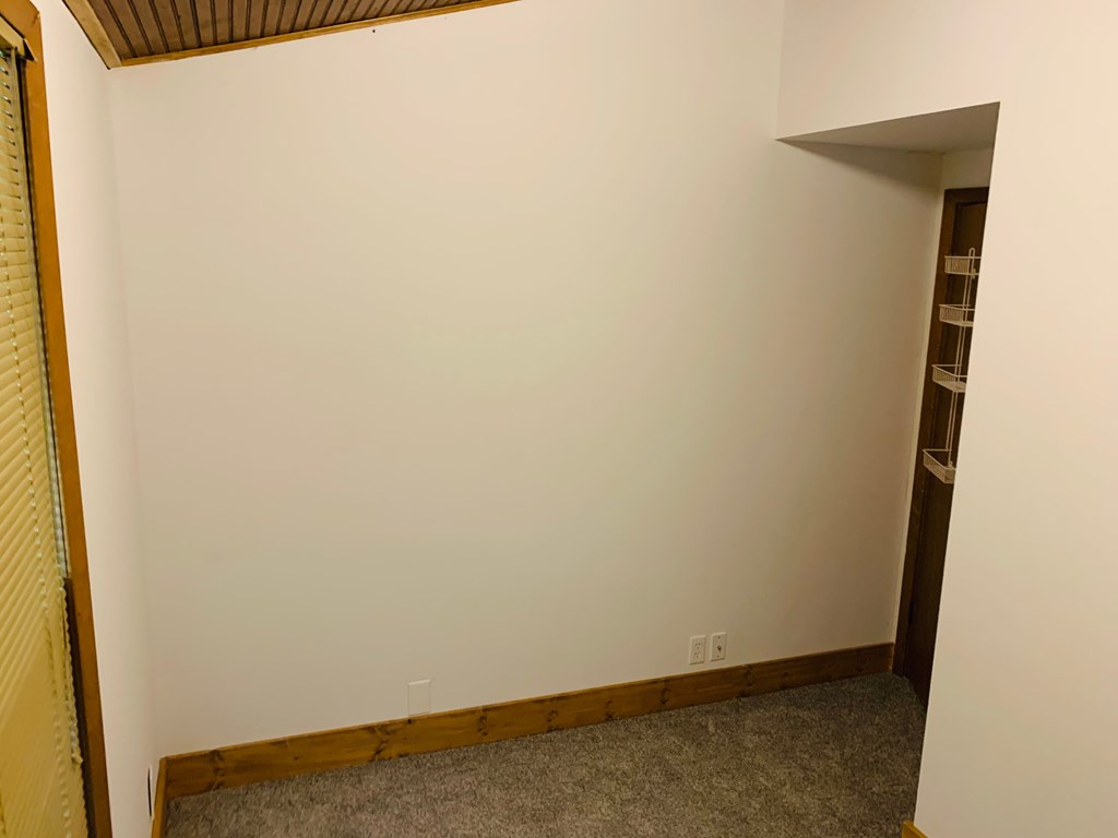 a room with white walls and a door and a bookshelf