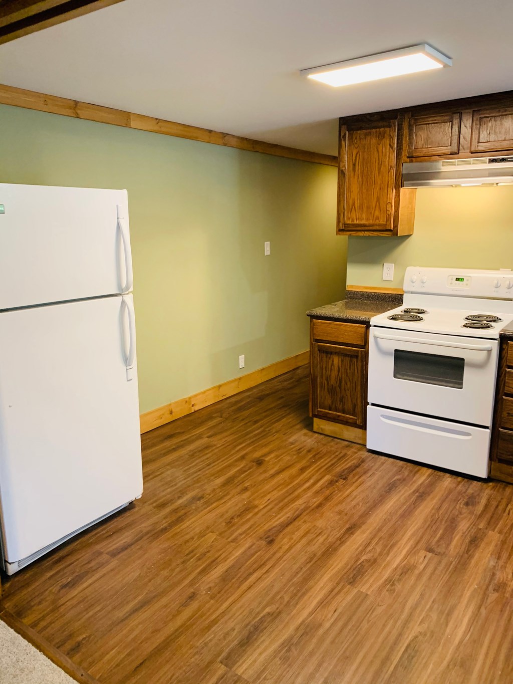 a kitchen with white appliances and wooden floors and a refrigerator