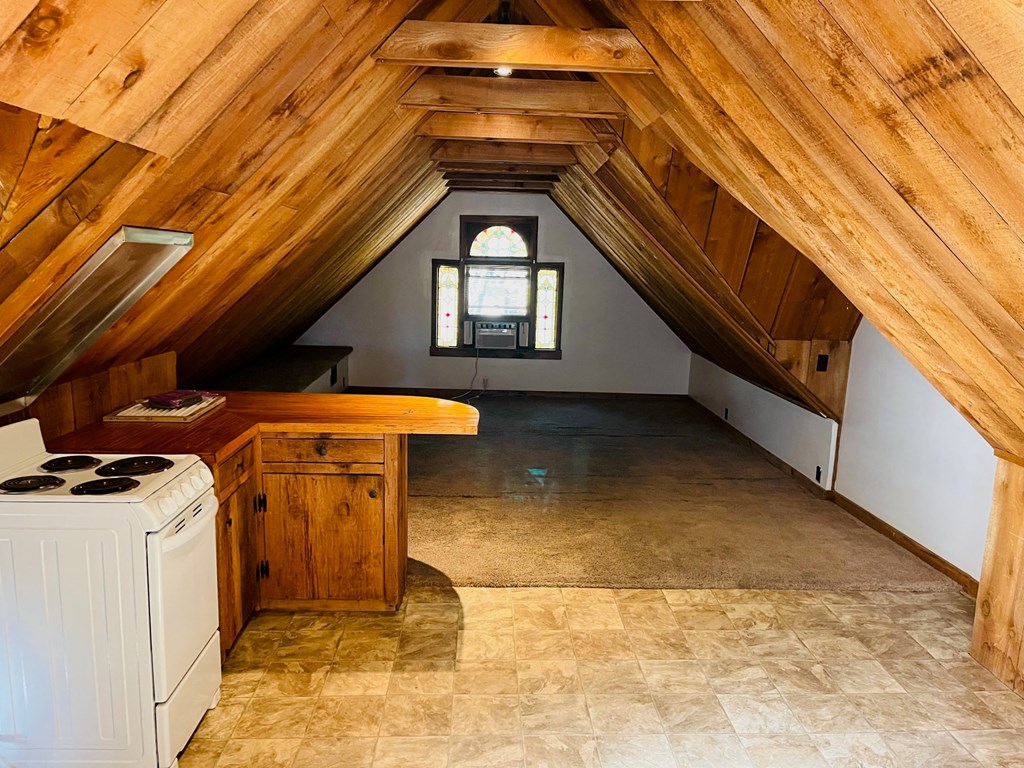 an attic with a kitchen and a stove and a window