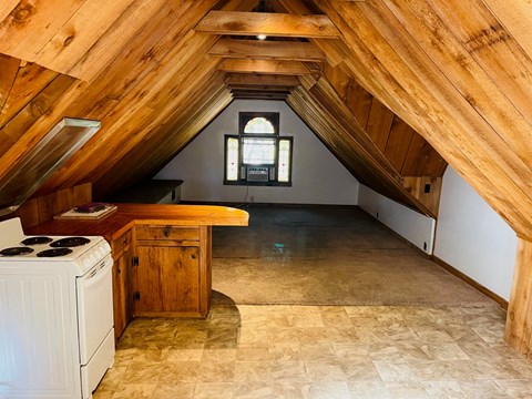 an attic with a kitchen and a stove and a window