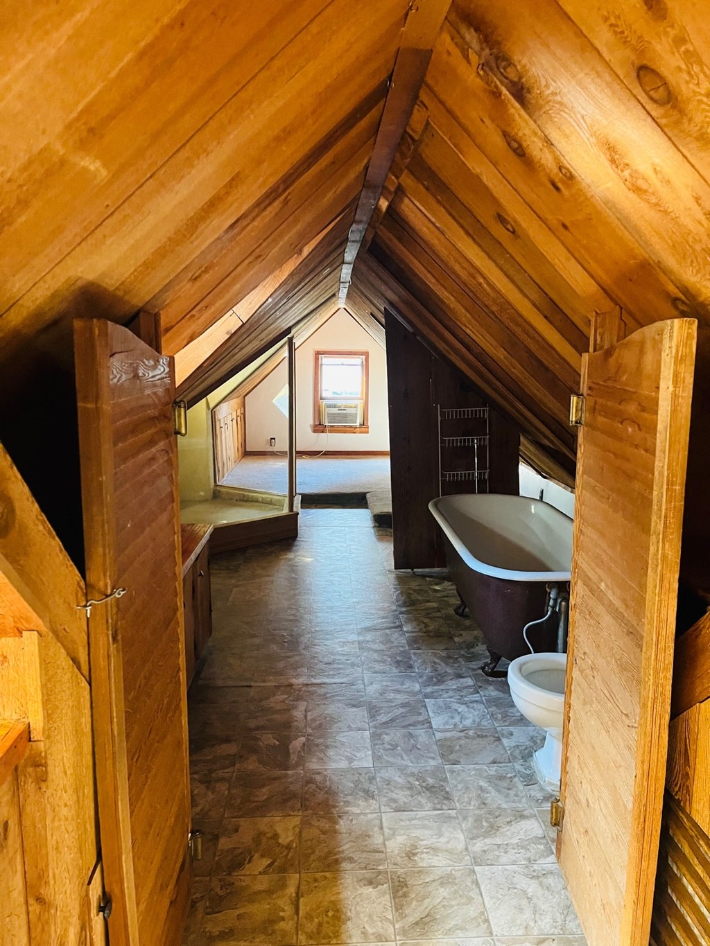 the attic of a cabin with a bathroom and a bath tub