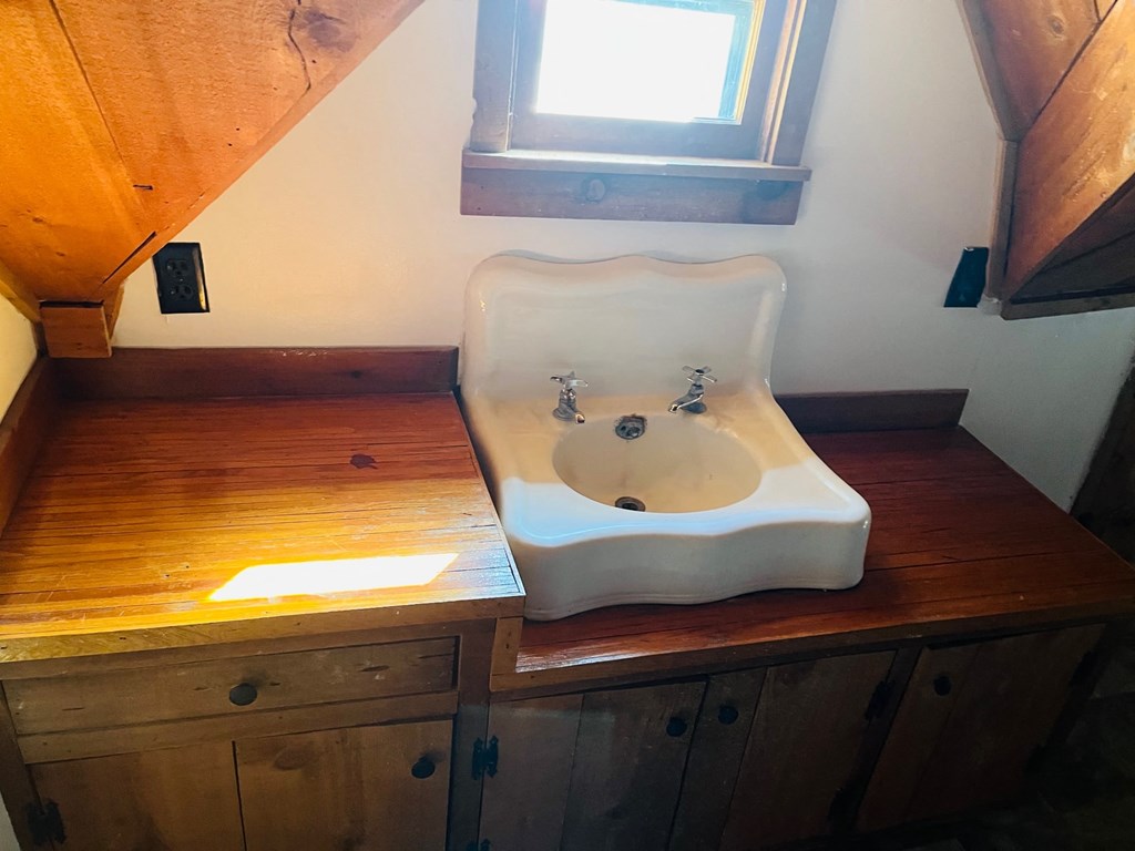 a white sink sitting on top of a wooden counter with a window