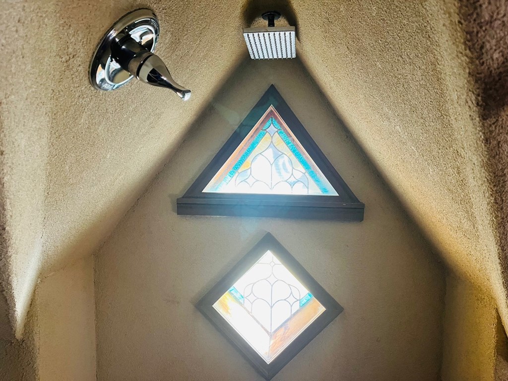 a trio of stained glass windows hanging on a wall with a light