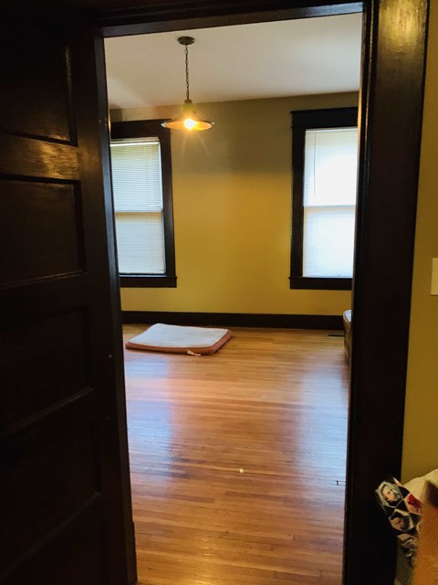 a living room with a hard wood floor and two windows