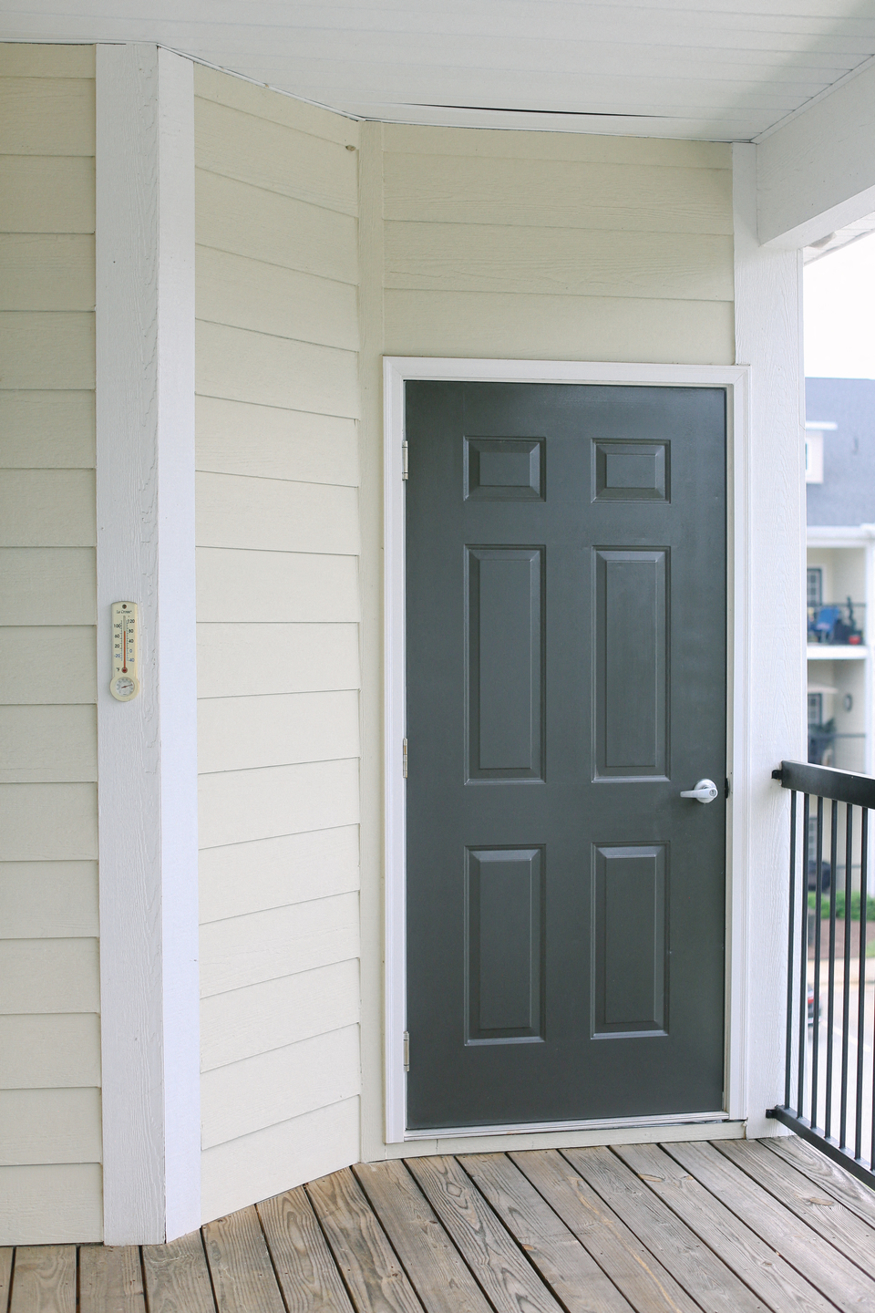 a black door on a white house with a porch