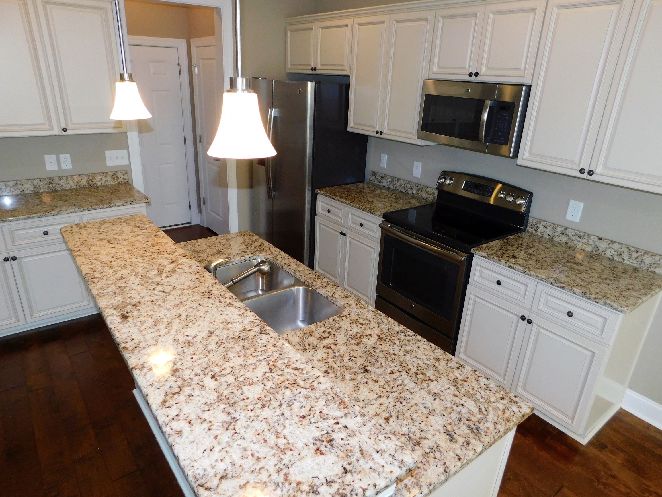 a kitchen with white cabinets and granite counter tops