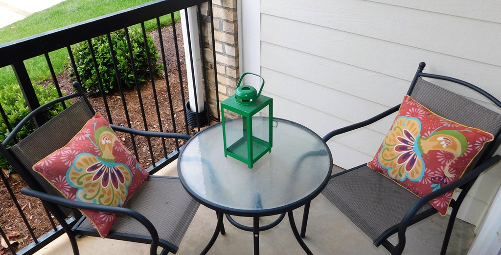 a patio with a glass table and chairs and a green lantern