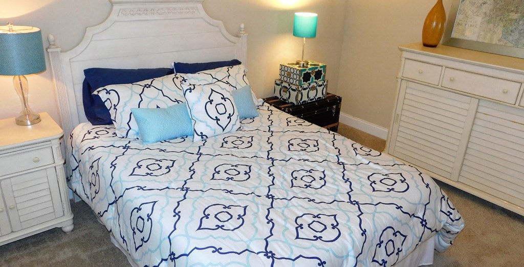 a bedroom with a bed and a blue and white comforter