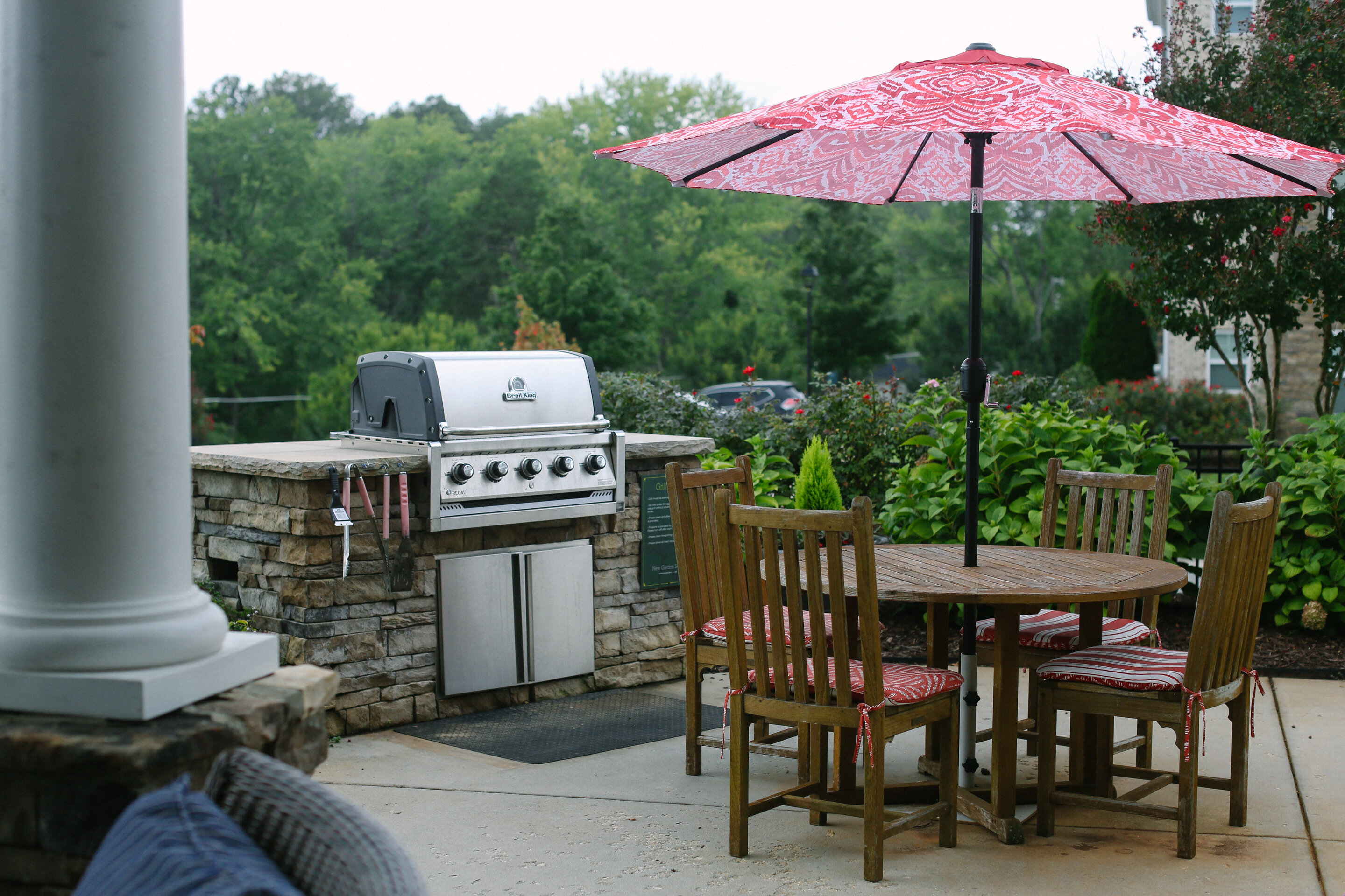 a patio with a grill and a table with chairs and an umbrella