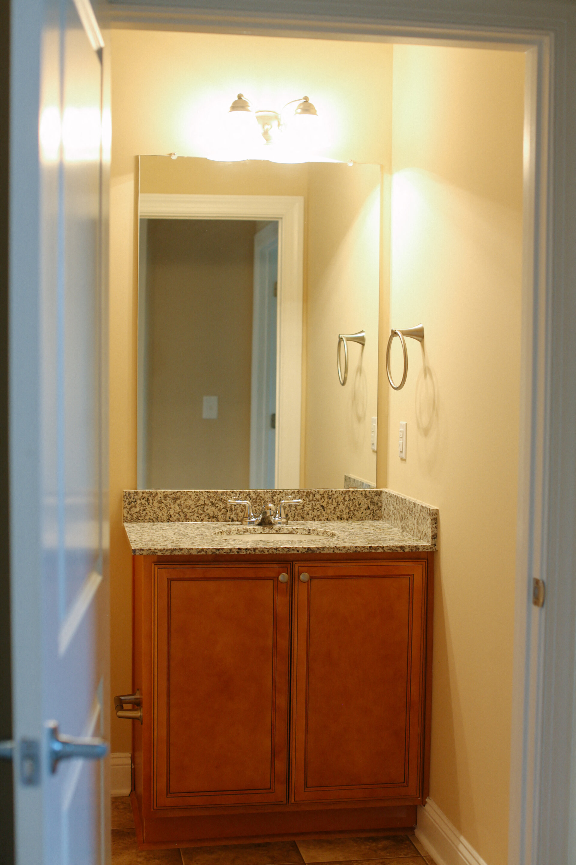 the bathroom has a granite counter top and a large mirror