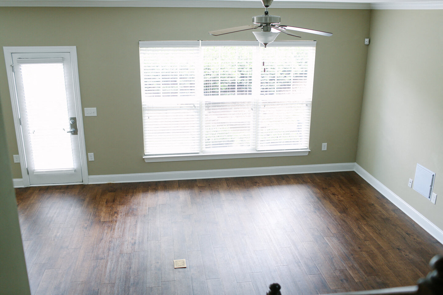 an empty living room with wood floors and a large window