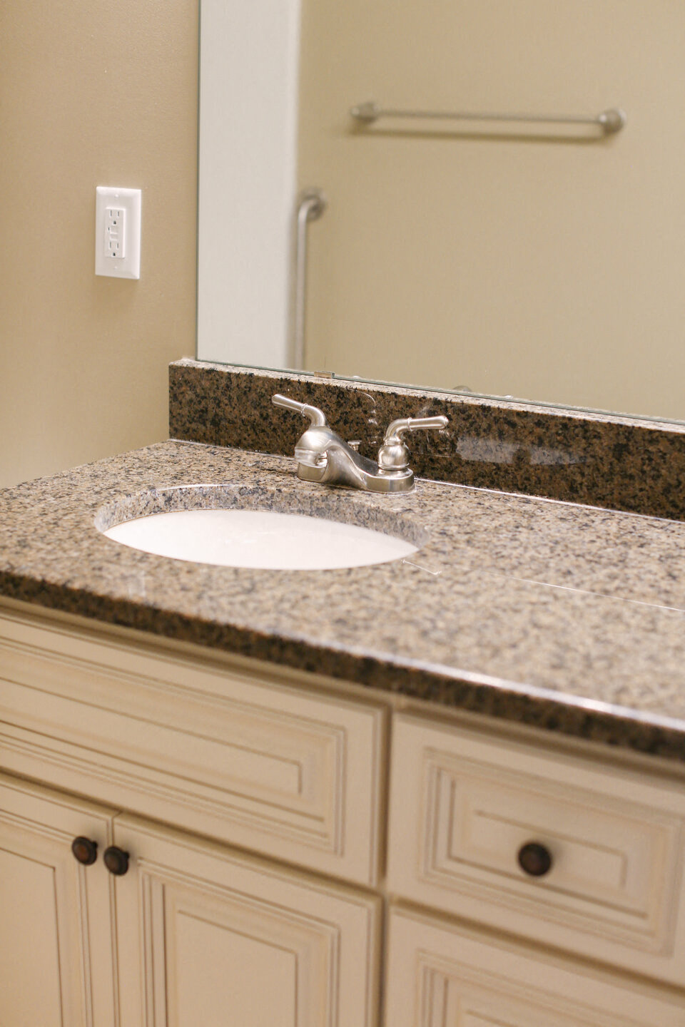 a bathroom sink with granite counter top and a mirror