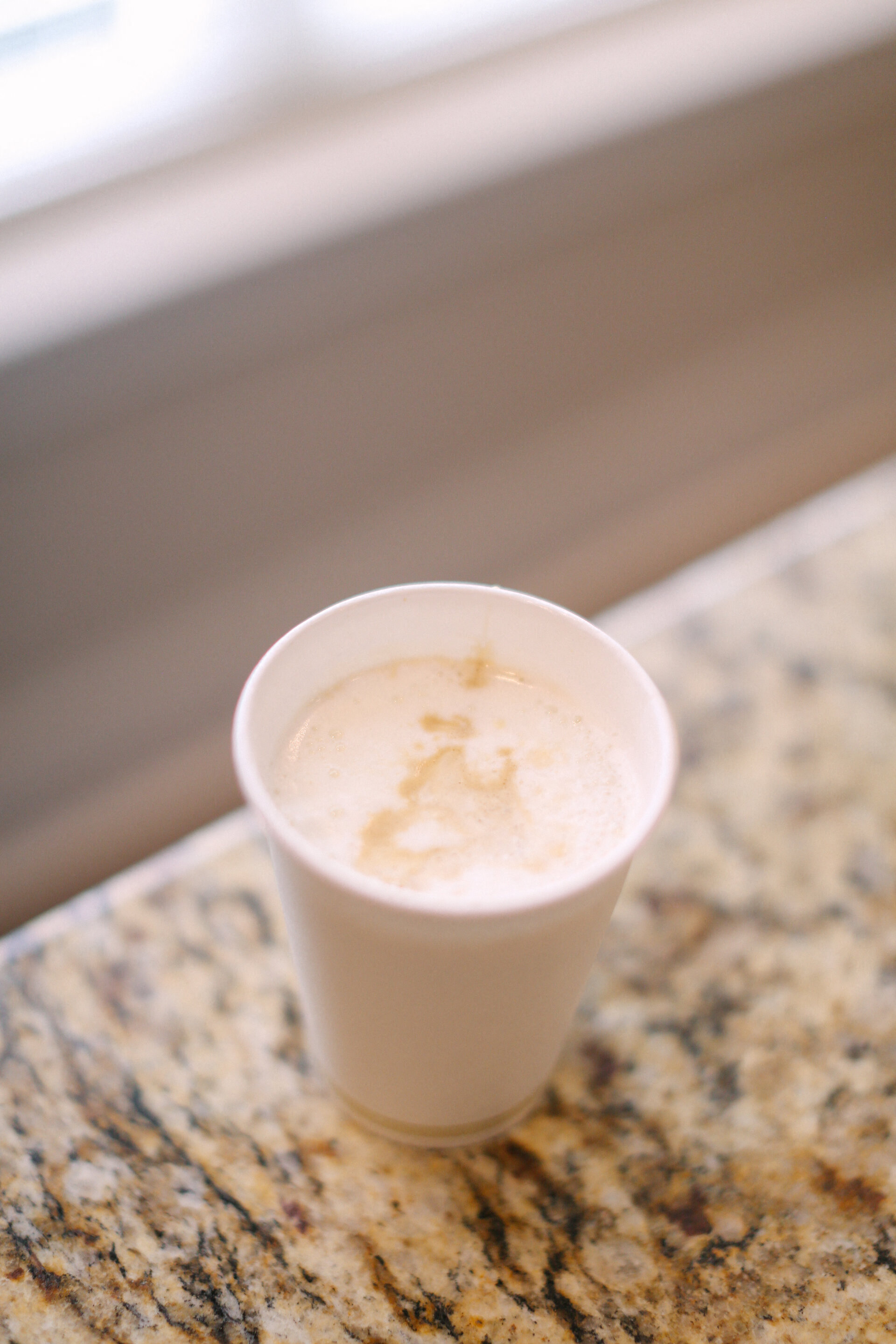 a cup of coffee on a counter next to a window