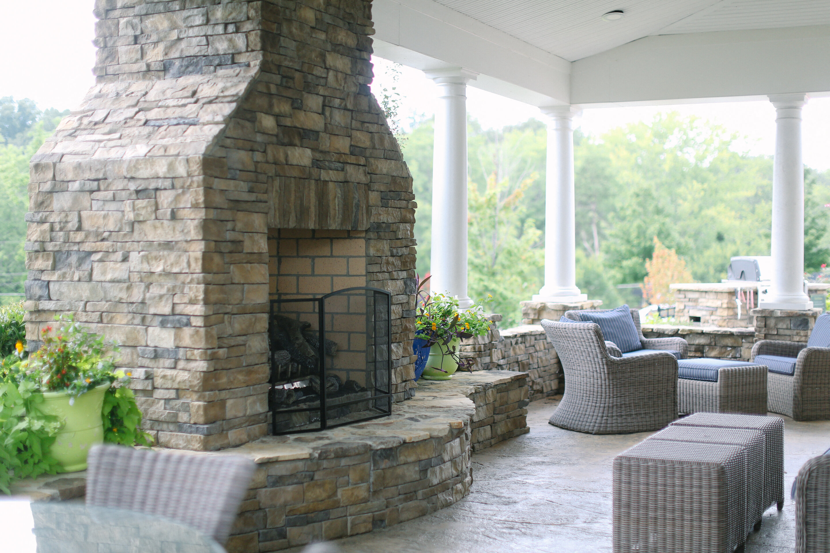 a stone fireplace on a covered patio with furniture