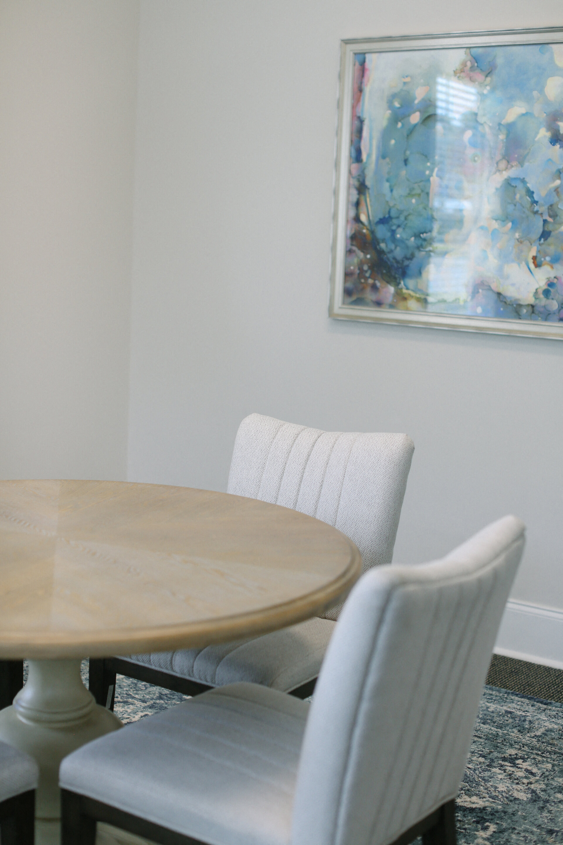 a dining room table with chairs and a painting on the wall