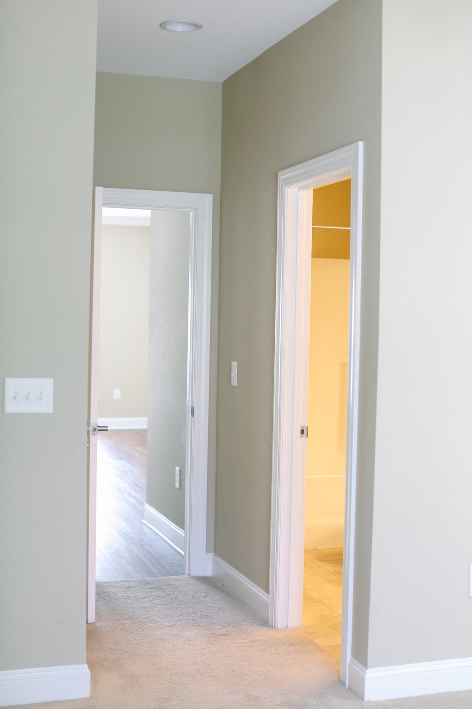 an empty room with a door open to a hallway and a door to a bedroom
