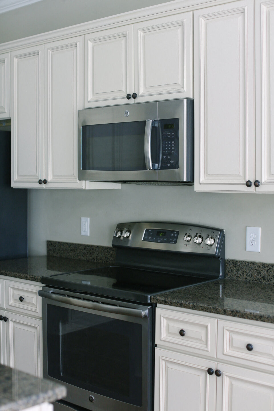 a kitchen with white cabinets and a stove and a microwave