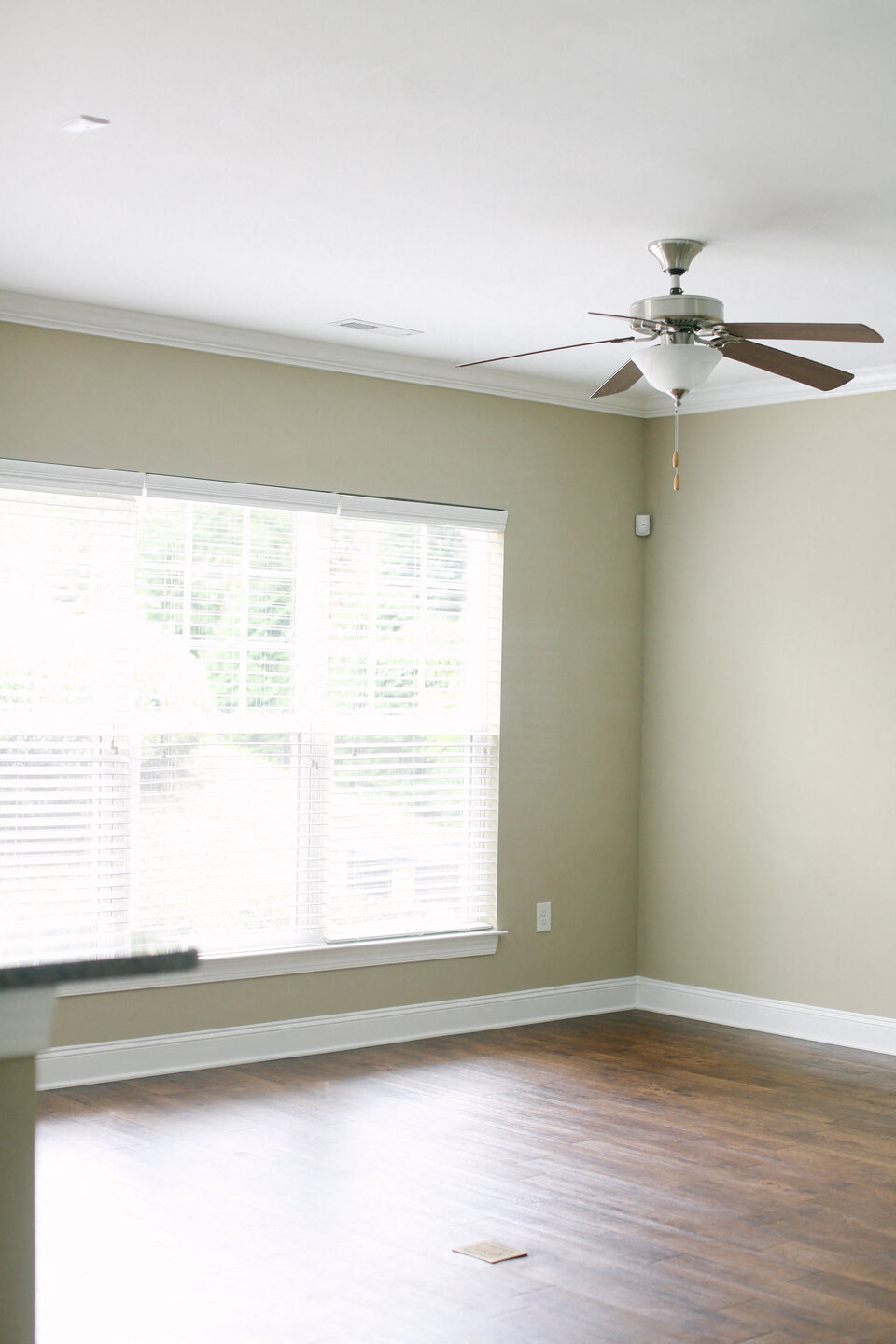 a living room with a ceiling fan and a large window