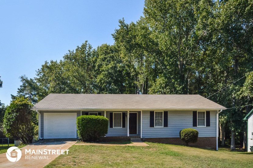 a small white house with a lawn and trees