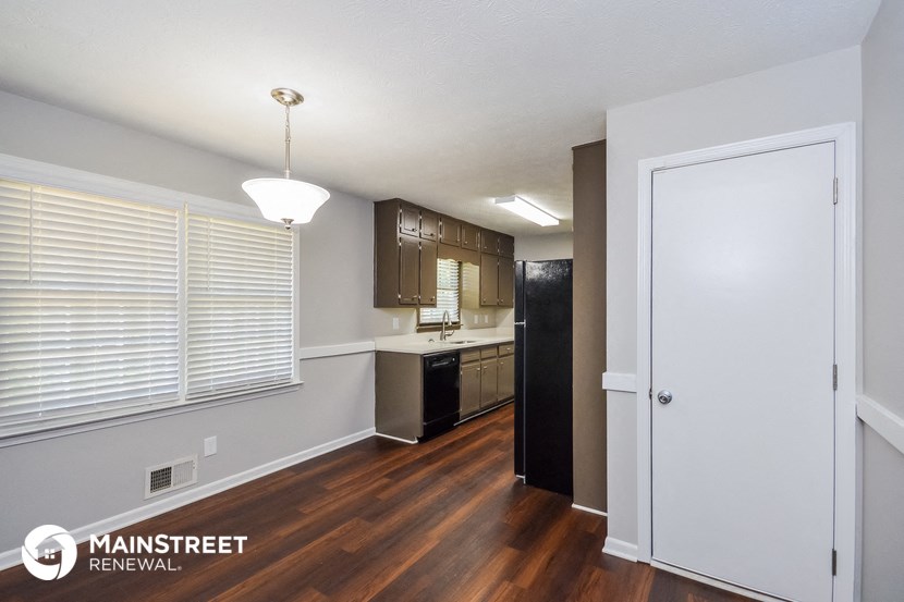 the kitchen of an apartment with wood flooring and a large window