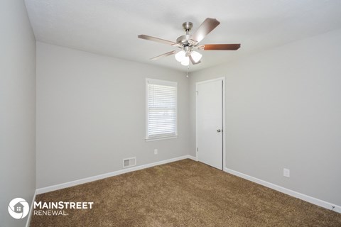 the spacious living room with ceiling fan and carpet