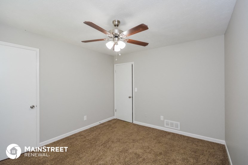 the spacious living room with ceiling fan and carpet