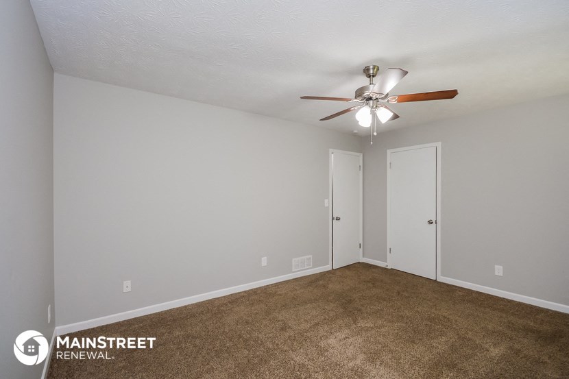the spacious living room with ceiling fan and carpet