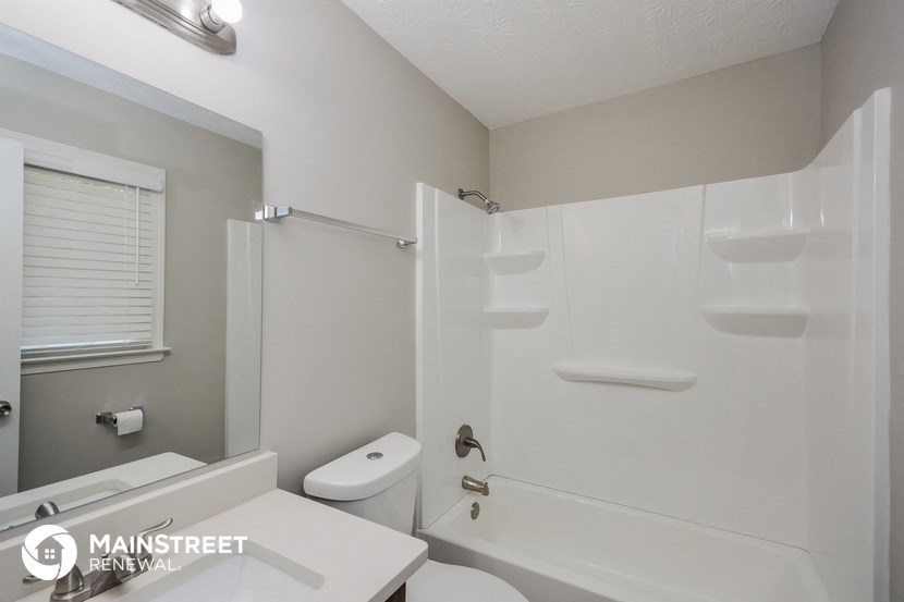 a white bathroom with a shower toilet and sink