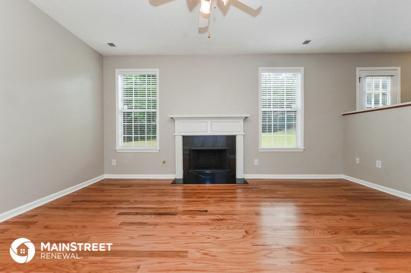 the living room with wood floors and a fireplace