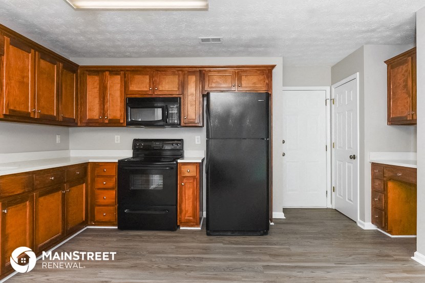 a kitchen with wooden cabinets and a black refrigerator