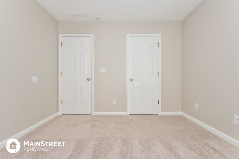 a bedroom with two white doors and a carpeted floor